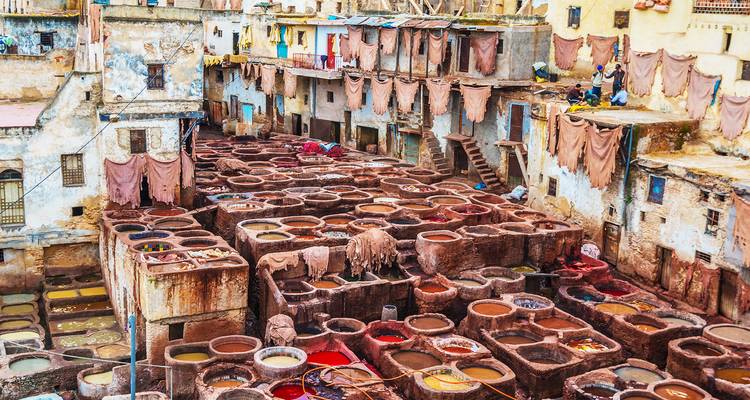 Bunte Steinbottiche der Chouara-Gerberei in Fes, umgeben von verwitterten Gebäuden und Arbeitern.