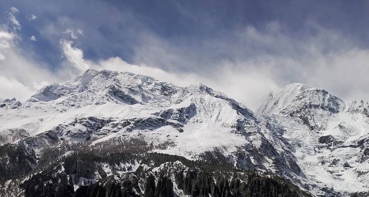 Línea del horizonte dentada del Himalaya con nubes arremolinadas y crestas cubiertas de nieve