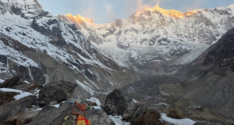 Sun-kissed Himalayan summits glow above a deep glacier-carved valley at dawn.