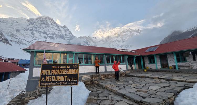 Travelers pose outside Hotel Paradise Garden surrounded by deep snow and soaring Himalayan walls.