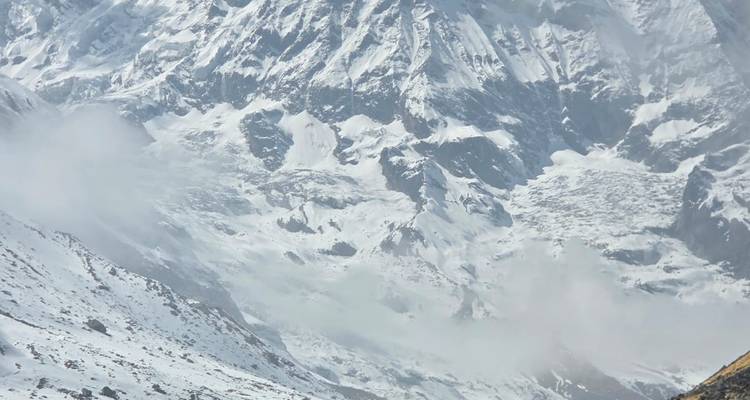 Detail of a rugged, snow-covered Himalayan mountainside partly shrouded in cloud.
