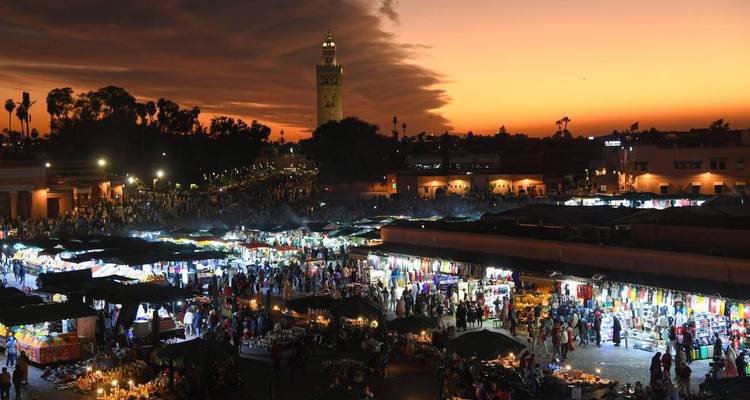 Weite Sonnenuntergangsaussicht über Marrakesch's Jemaa el-Fnaa Platz voller Marktstände.