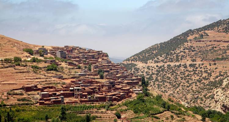 Traditionelles Berberdorf am Berghang, eingebettet zwischen trockenen Terrassentälern.