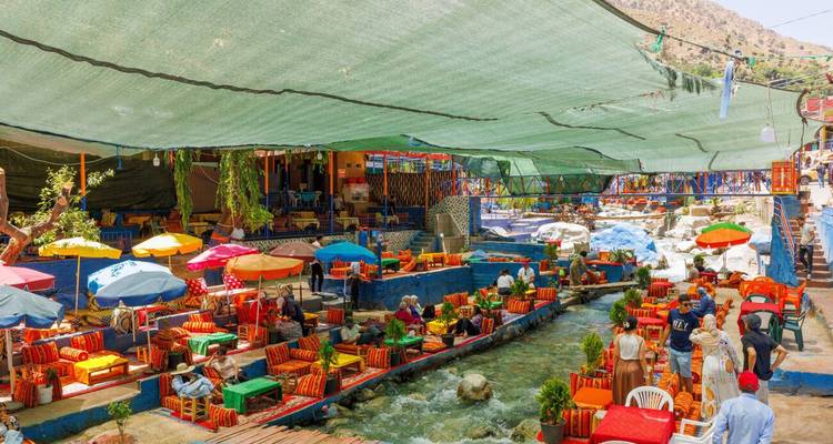 Lebendige Flussufer-Restaurants mit bunten Sonnenschirmen im Ourika-Tal.