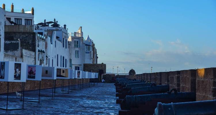Steinerne Festungsmauern mit historischen Kanonen und Fotoausstellung im Freien in Essaouira.