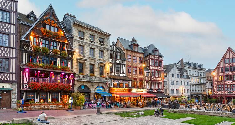 Colourful timber-framed houses and lively café terraces in Rouen old town at evening lights.