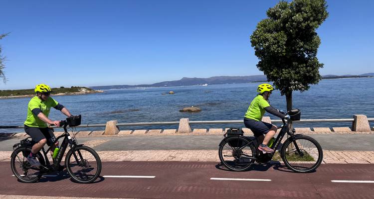 Recreatieve fietsers volgen een fietspad langs de kust naast rustig blauw water
