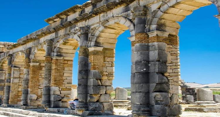 Ancient Roman stone arch ruins of Volubilis under blue sky
