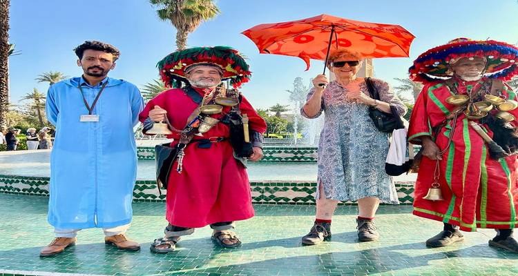Travelers posing with traditional water sellers holding brass cups by fountain