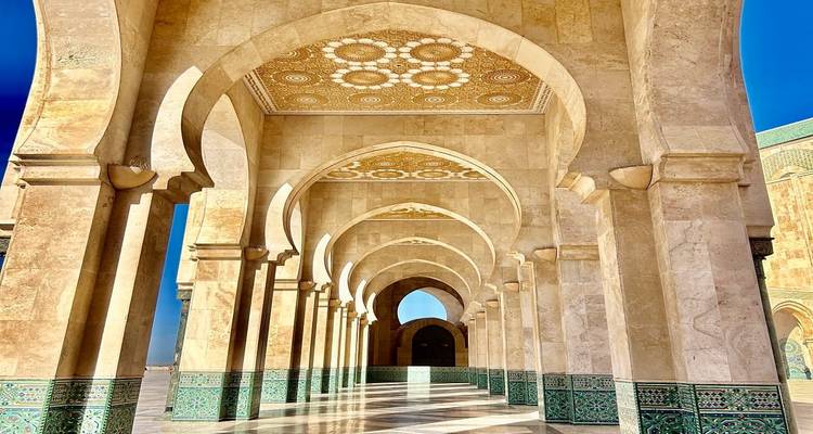 Elegant marble and mosaic arcade of Hassan II Mosque lit by bright sun