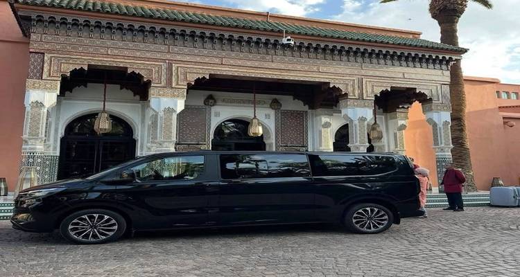Black tour van parked in front of ornate arched entrance of Moroccan riad hotel