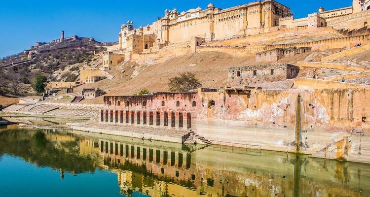 Fort d'Amber se reflétant dans le lac Maota avec des murs de grès ensoleillés et un ciel bleu.