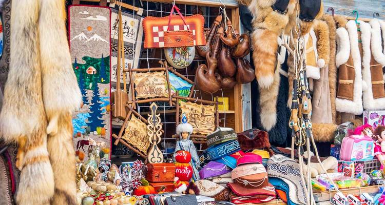 Étal de marché coloré rempli d'artisanat traditionnel, de fourrures, de chapeaux en feutre et de souvenirs.