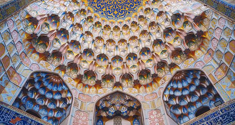 Plafond aux muqarnas éblouissant avec des motifs géométriques et floraux complexes à l'intérieur d'une madrasa historique.