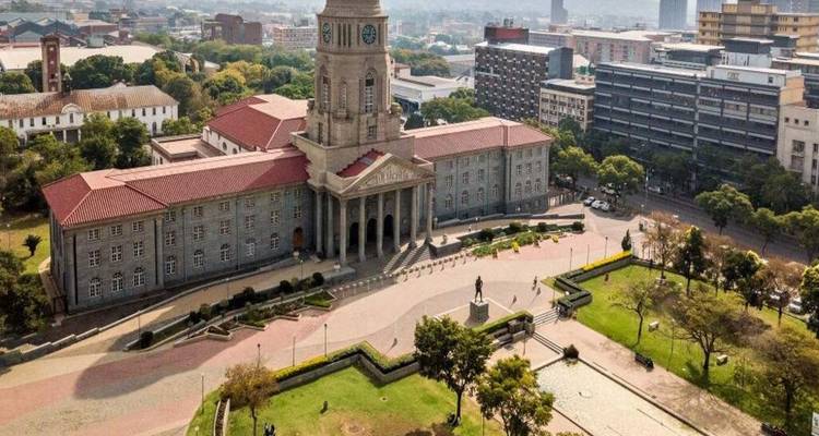 Aerial view of an imposing civic building with red roof surrounded by urban Johannesburg streets.