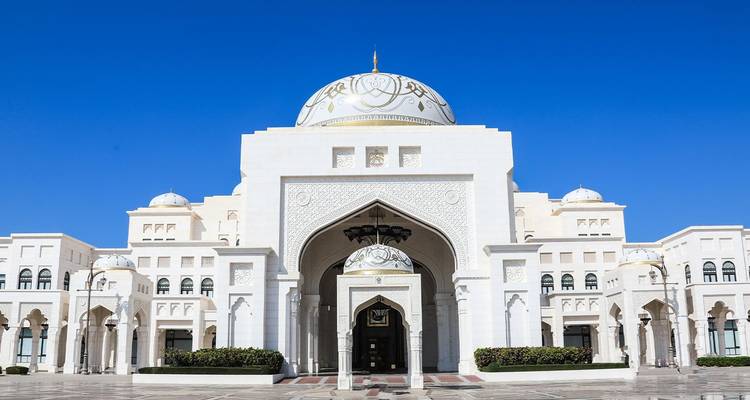 Elegant white facade and central dome of Qasr Al Watan presidential palace under clear blue sky.