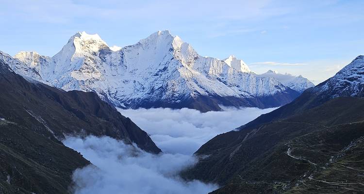 Spectaculair Himalaya panorama met torenhoge besneeuwde toppen die uitsteken boven een zee van wolken in een steile vallei.