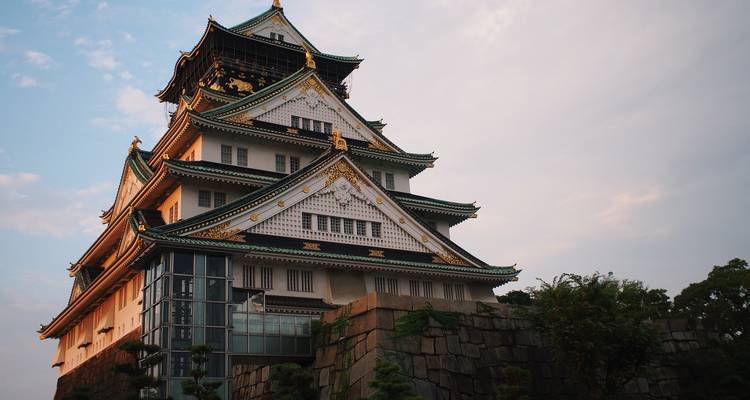 Close-up perspective of Osaka Castle bathed in warm evening light against a pastel sky.