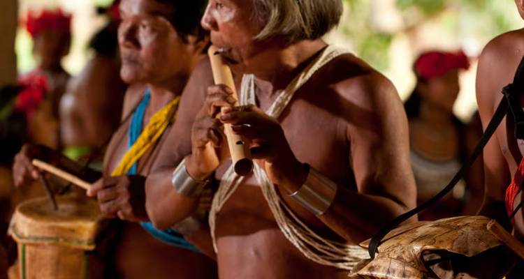 Gedetailleerde weergave van leden van de Embera-gemeenschap die traditionele instrumenten bespelen tijdens een dorpsceremonie.