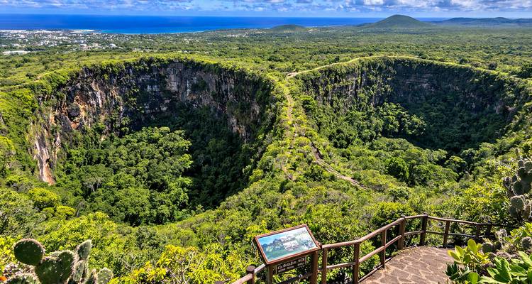 Twin volcanic pit craters of Los Gemelos blanketed in lush forest with ocean glimpses beyond