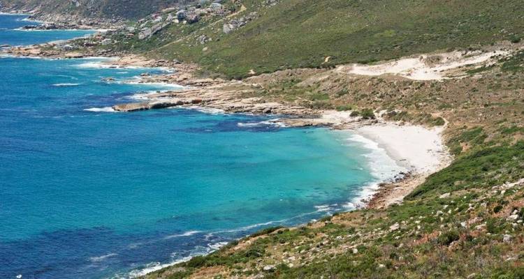 Plage de sable blanc isolée et eaux turquoise le long de la côte escarpée de la péninsule du Cap