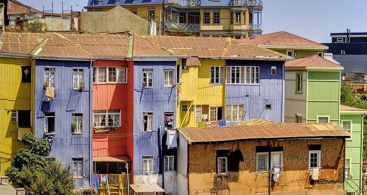 Hilera de casas coloridas pintadas en la ladera en colores variados bajo cielos despejados.