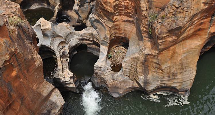 Vista aérea de pozas de arenisca esculpidas y agua arremolinada en el Cañón del Río Blyde.