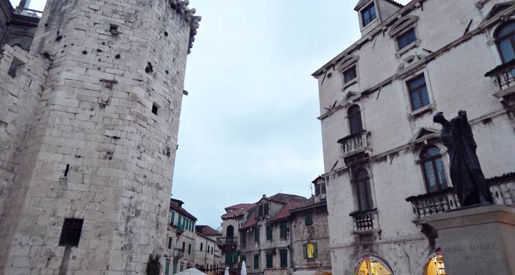Scène en soirée de la vieille ville de Split avec tour en pierre, ruelles étroites et façades historiques.