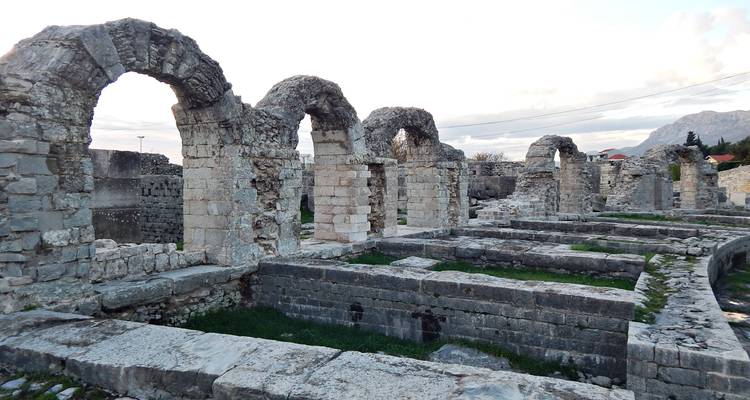 Rangée de ruines de pierre voûtée avec des cours herbues, mettant en évidence l'architecture de l'époque romaine.