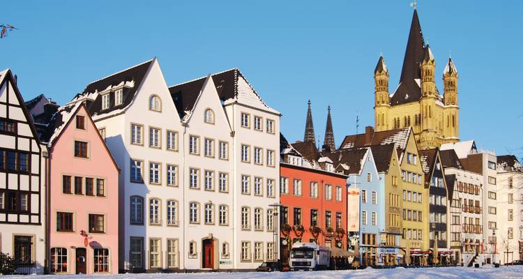 Row of pastel-colored historic houses and the towering Great St. Martin Church under a clear blue winter sky.