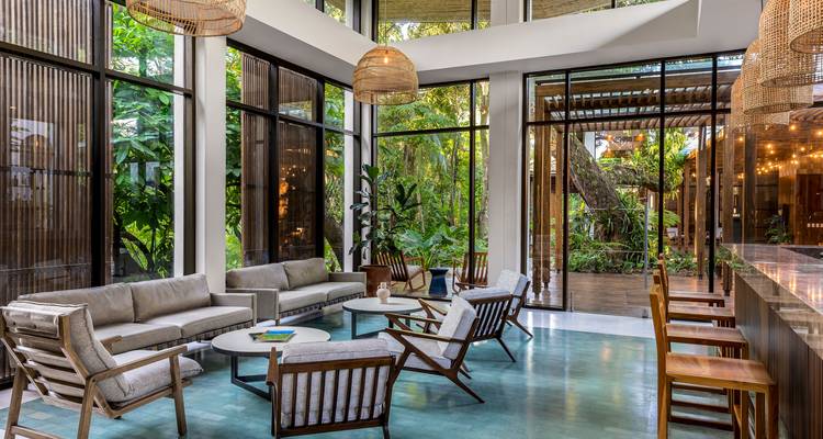 Bright contemporary lobby with glass walls, rattan lamps and stylish seating.