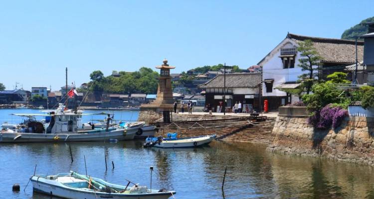 Quaint harbor with fishing boats, stone wharf and lighthouse in a seaside village.