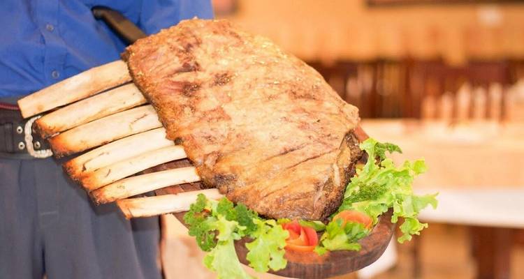 Large rack of slow-roasted ribs presented on a wooden board with lettuce and tomato garnish