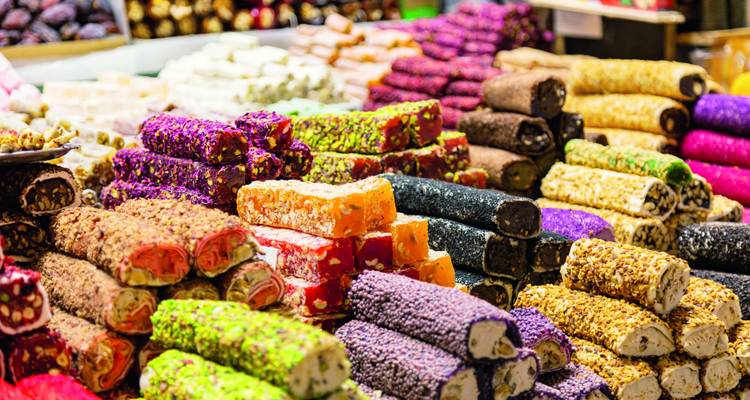 Bunte Stapel verschiedener türkischer Süßigkeiten, angeordnet in einem geschäftigen Basarstand.