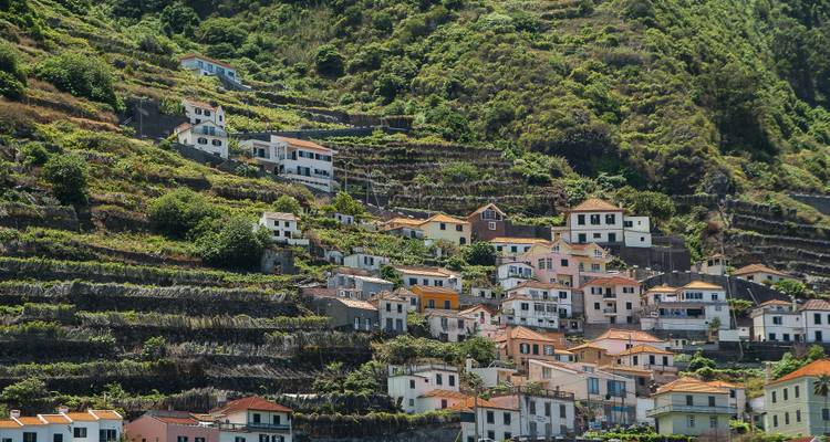 Steep terraced hillsides dotted with colorful houses and dense green vegetation.