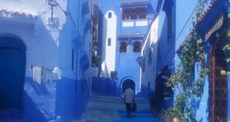 Stille blauw gekalkte steeg in Chefchaouen met eenzame figuur die wegloopt