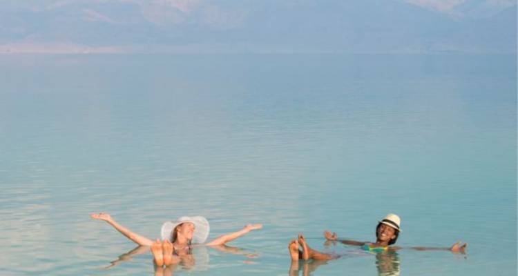 Twee reizigers drijven moeiteloos op het kalme turquoise water van de Dode Zee