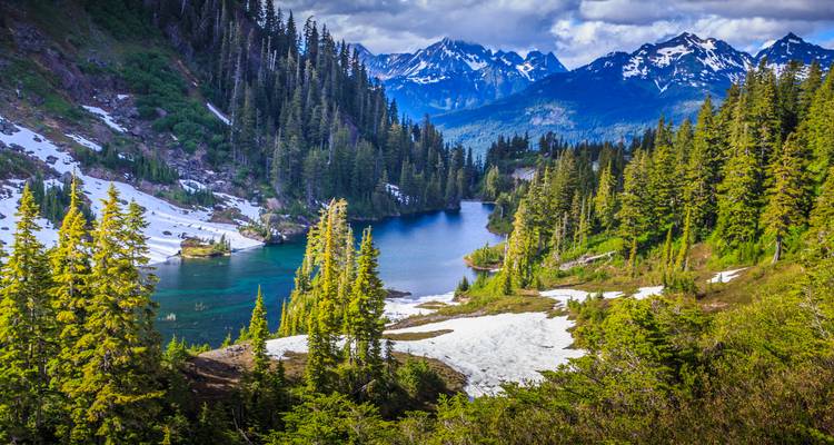 Alpine lake surrounded by evergreen forests and snow-capped peaks in Glacier National Park