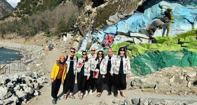 Des voyageurs portant des vestes assorties posent sur un sentier rocheux de montagne à côté d'une fresque murale représentant un renard roux.