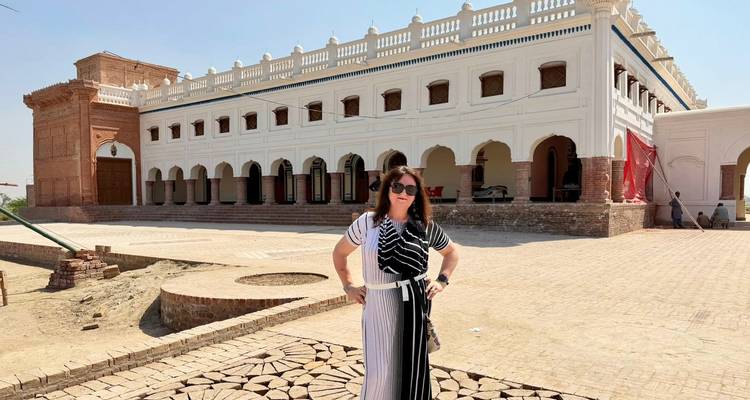 Un visiteur se tient devant un palais colonial blanc restauré avec des arcs décoratifs.