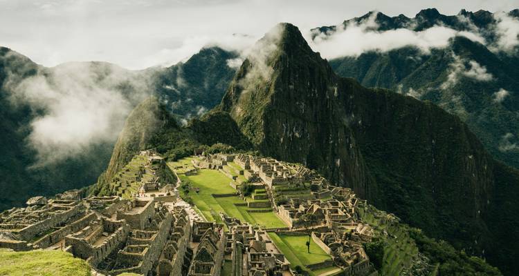 Dramatische Wolken wirbeln über einem nebelumhüllten Machu Picchu und heben seine Terrassen und den Gipfel des Huayna Picchu hervor.
