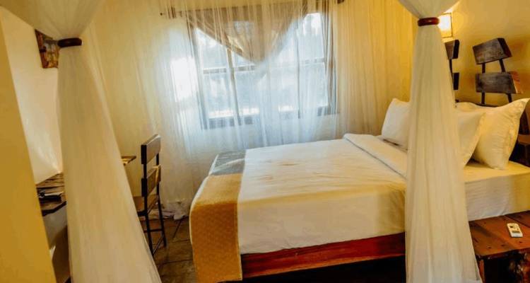 Cozy lodge bedroom with mosquito-net draped bed and warm lighting