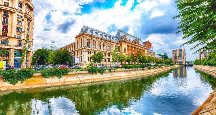 Helder bewerkte weergave van Boekarest's riverside architectuur weerkaatst in kalm kanaalwater onder een gedeeltelijk bewolkte hemel