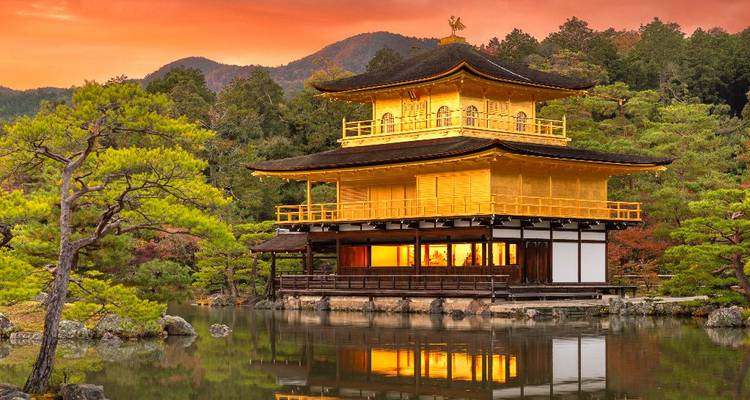 Gouden Paviljoen tempel weerkaatsend in een kalme vijver bij zonsondergang.