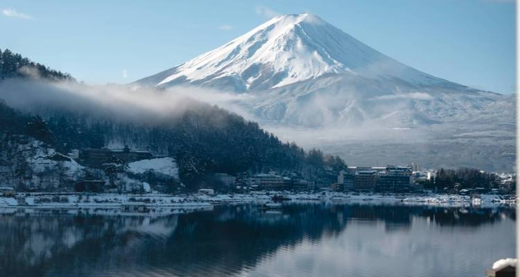 Le mont Fuji saupoudré de neige se reflète dans les eaux calmes du lac Kawaguchi enveloppé de brume.