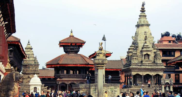 Crowds gather among stone temples and monuments in Bhaktapur’s historic square on a bright day