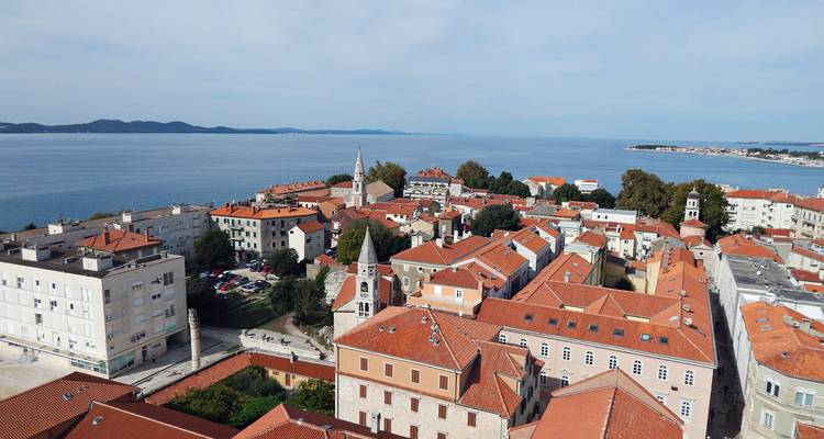 Dachterrassen-Panorama einer in die Adria ragenden alten Stadt mit umgebender Küstenlinie.