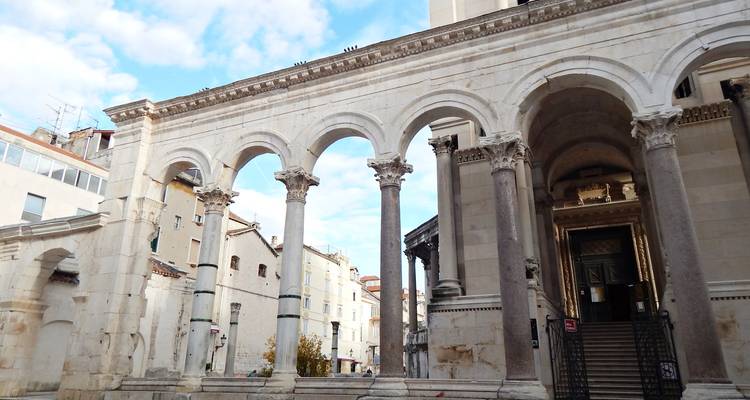 Colonnade élégante en marbre et arches dans une cour de palais historique.