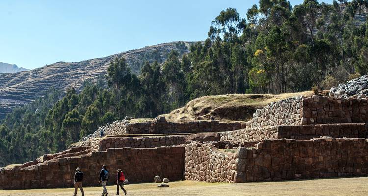 Travelers explore broad stone terraces framed by eucalyptus forests and distant ridges.