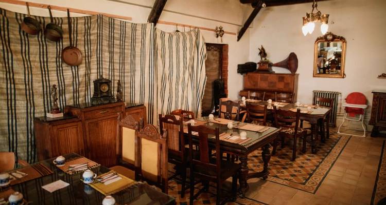 Salle à manger vintage avec antiquités éclectiques, séparateurs en tissu rayé et sol en carreaux à motifs.